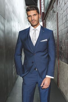 a man in a blue suit standing next to a wall