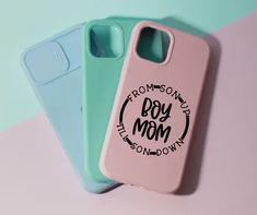 three phone cases sitting next to each other on a pink, blue and green surface