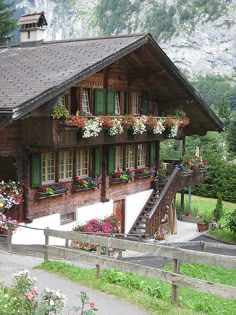 a wooden house with flowers on the balcony