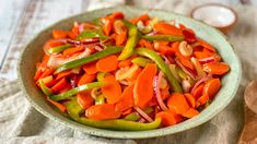 a bowl filled with sliced up vegetables on top of a table next to a wooden spoon