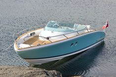 a small blue and white boat floating on top of a lake next to a rocky shore