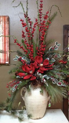 a white vase filled with red flowers on top of a table