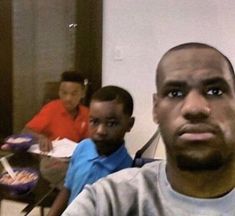 three young men sitting at a table with plates of food in front of them,