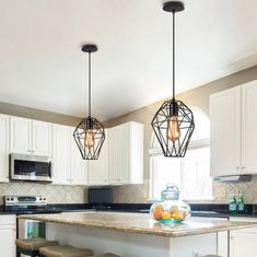 three lights hanging over a kitchen island with stools in front of it and an oven on the other side