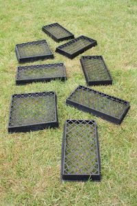 six black plastic trays sitting in the grass