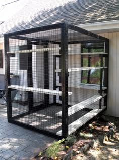 a black caged enclosure sitting on the side of a house