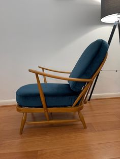 a blue chair sitting on top of a hard wood floor next to a light fixture