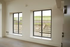 an empty room with large windows and stairs