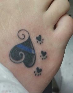 a tattoo on the foot of a person with a dog paw and blue ribbon around it