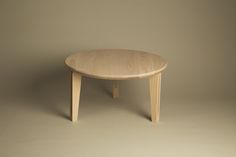 a round wooden table with two legs on an off - white background, it appears to be made out of wood