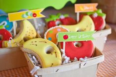 there are many decorated doughnuts in the basket on the table and one has a sign that says happy birthday