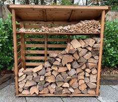 a pile of wood sitting in a wooden crate on top of a stone floor next to shrubbery