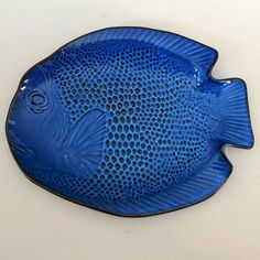 a blue fish shaped dish sitting on top of a white countertop next to a wall