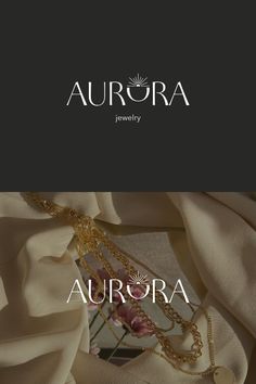 the logo for aurora jewelry is shown on top of a white cloth with gold chains