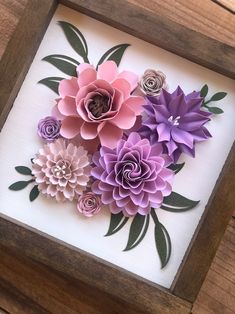 paper flowers in a wooden frame on a table