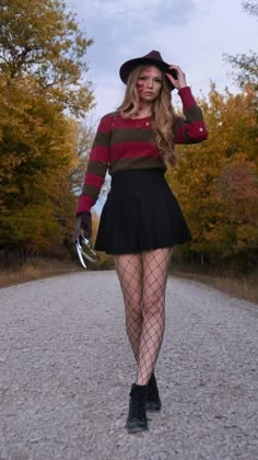 a woman wearing fishnet stockings and tights is standing on a gravel road with trees in the background