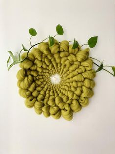 a circular arrangement of green leaves on a white background, with the center surrounded by yellow spirals