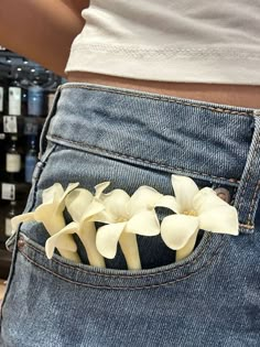 a woman's stomach with flowers in the back pocket of her jean pants,