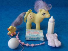 the toy pony is next to its toys on the blue surface with eggs and other items