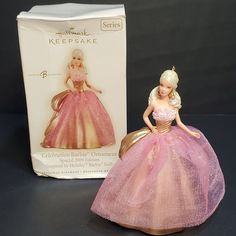 a barbie doll in a pink dress next to a box