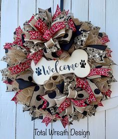 a welcome dog wreath is hanging on a door with the word welcome written in black, white and red