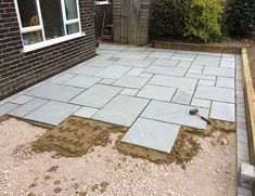 a brick patio being built in front of a house with tools laying on the ground