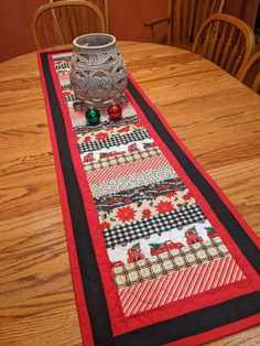 a table runner is sitting on top of a wooden table with a vase and christmas decorations