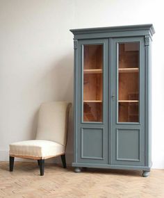 a chair sitting next to a cabinet with glass doors