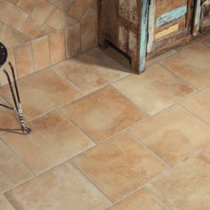 a chair sitting on top of a tiled floor next to a wooden cabinet and door