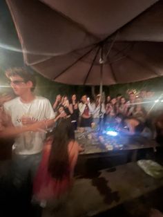 a group of people standing under an umbrella with their hands up in front of them