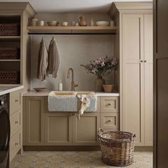 a washer and dryer in a small room with beige cupboards, cabinets and drawers