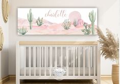 a baby's room with a white crib and pink watercolor cactus wall art