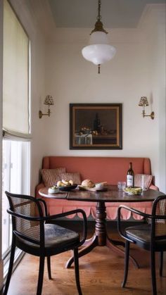 a dining room table with two chairs and a bottle of wine on top of it