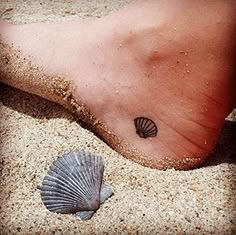 a small tattoo on the foot of a person with a seashell and starfish