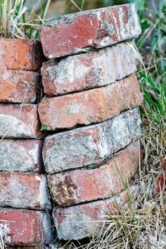 a pile of red bricks sitting on top of dry grass and dead grass covered ground