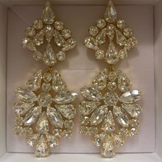 two pairs of earrings in a box with some diamonds on the bottom and one is gold