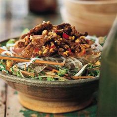 a bowl filled with meat and veggies on top of a wooden table