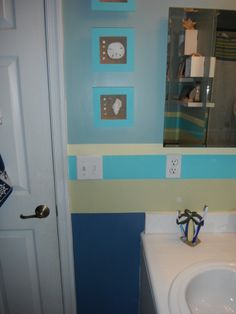 there is a bathroom with blue and yellow stripes on the walls, along with a white sink