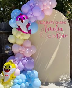 a baby shark balloon arch with balloons attached to it's sides and the words, our baby shark amelia is one