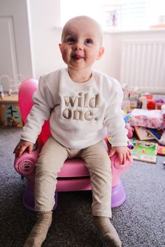 a baby sitting on top of a pink chair