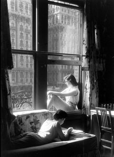 black and white photograph of two people sitting on a couch in front of a window