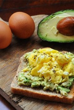 an avocado and egg sandwich is on a wooden cutting board