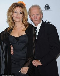 an older man and woman standing next to each other on the red carpet at an event