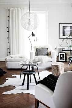 two pictures of a living room with white furniture and wood floors, one in black and white