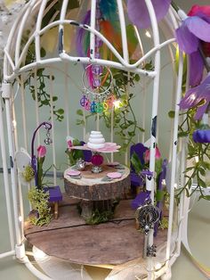 a white birdcage filled with lots of flowers and jewelry sitting on top of a wooden table