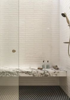 a bathroom with a marble counter top and shower head in the corner, along with black and white tile flooring