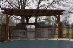 an outdoor bbq and grill area with trees in the background