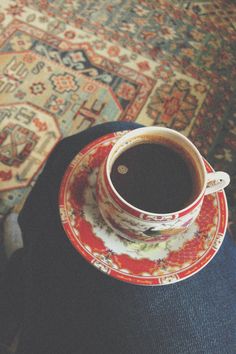 a cup of coffee sitting on top of a saucer in front of a rug