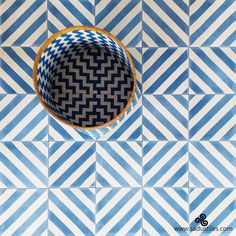 a bowl sitting on top of a blue and white tiled floor next to a basket