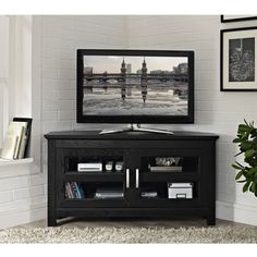 a flat screen tv sitting on top of a black entertainment center next to a potted plant